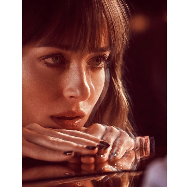 Close-up portrait of a woman with dark hair leaning on her hands, displaying polished nails. Studio lighting and shallow depth of field.