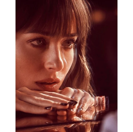 Close-up portrait of a woman with dark hair leaning on her hands, displaying polished nails. Studio lighting and shallow depth of field.