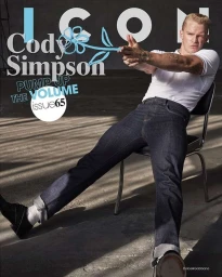 Cody Simpson seated backward on a metal chair wearing a white polo shirt and cuffed dark denim jeans by photographer Carter Smith.