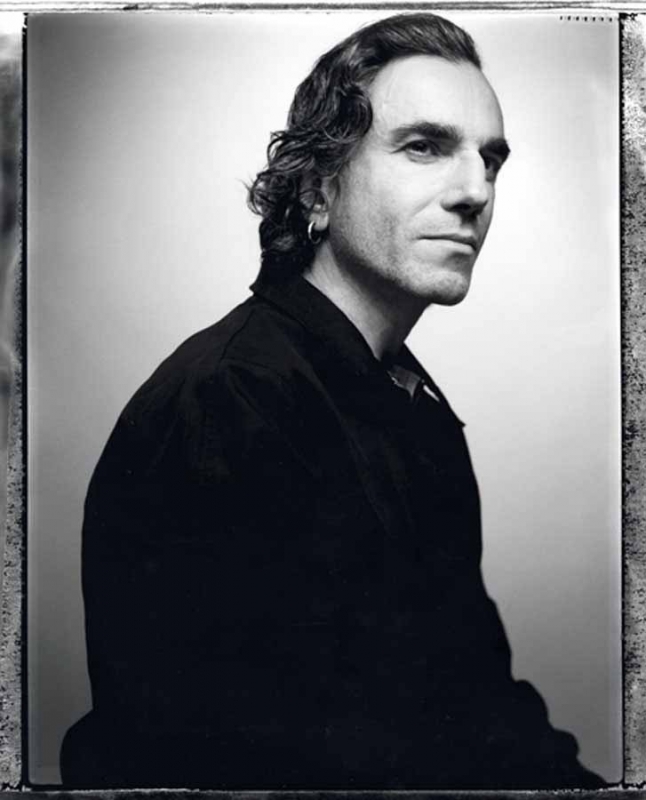 Black and white portrait of an adult male with dark hair, wearing a collared shirt, against a neutral light background in a photo studio.