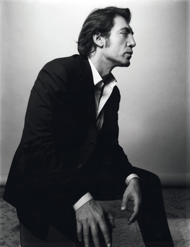 Portrait of a middle-aged man wearing a black suit and white shirt, seated indoors, looking off to the side in a black and white photograph.
