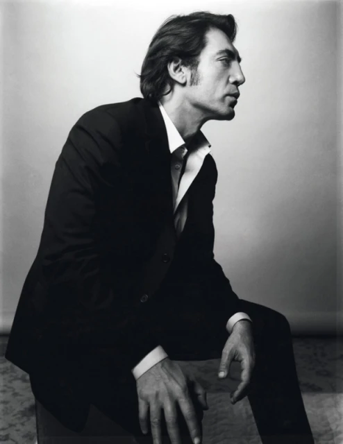 Portrait of a middle-aged man wearing a black suit and white shirt, seated indoors, looking off to the side in a black and white photograph.