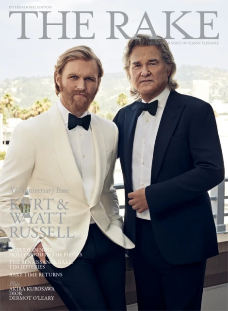 Magazine cover featuring Kurt and Wyatt Russell, both wearing tuxedos, against a backdrop of greenery and buildings in the background.