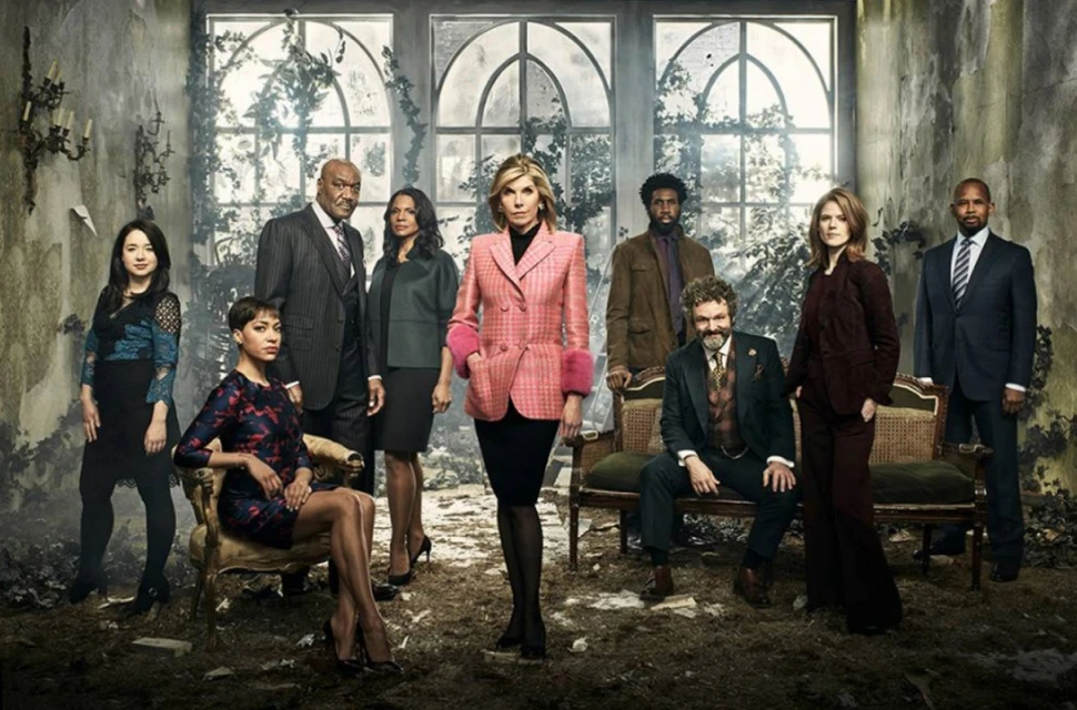 Group of diverse adult actors and actresses in formalwear pose for a promotional shot in an overgrown indoor set with large windows.