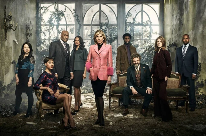Group of diverse adult actors and actresses in formalwear pose for a promotional shot in an overgrown indoor set with large windows.