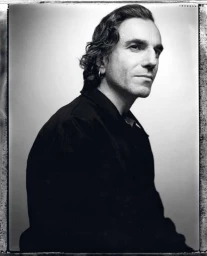 Portrait of Daniel Day-Lewis wearing a dark shirt and hoop earring against a plain light background by Justin Stephens