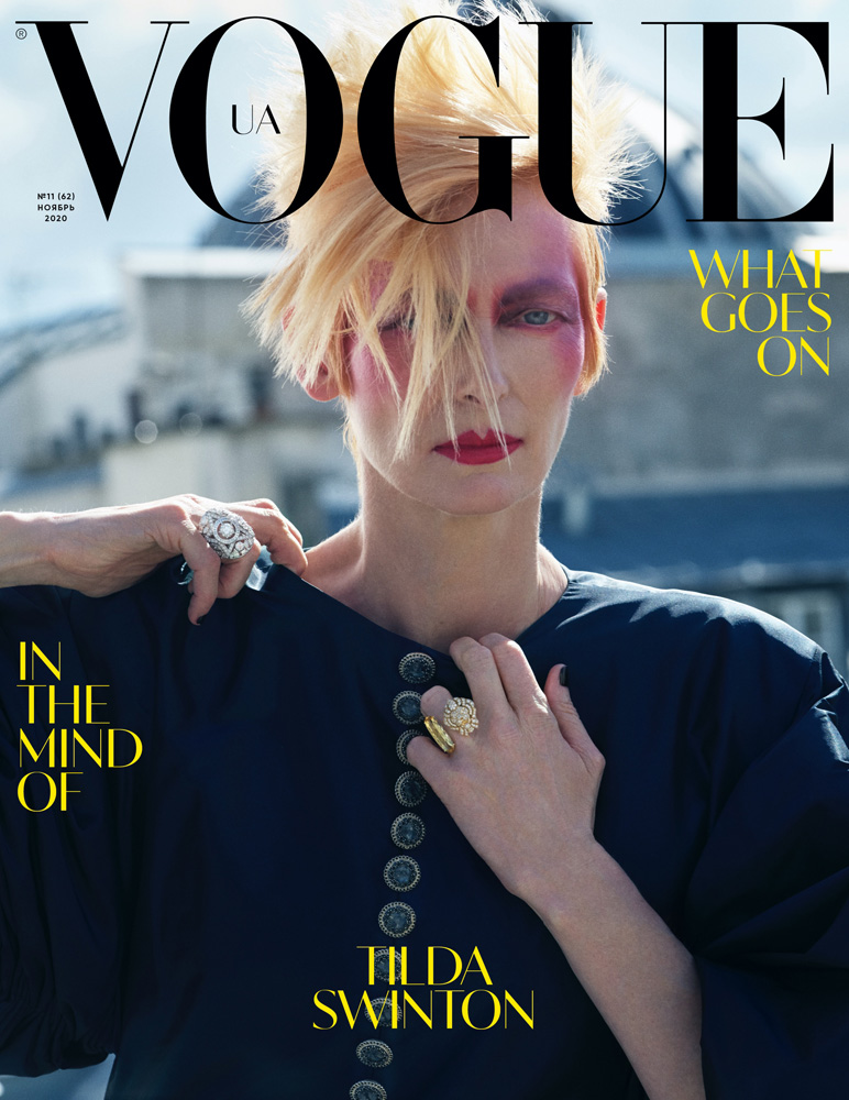 Vogue UA cover featuring Tilda Swinton in a blue button-down shirt and artistic makeup in an outdoor setting with architectural backdrop.