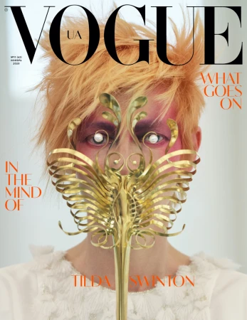 Vogue UA magazine cover featuring Tilda Swinton with golden hair, decorative golden mask, and pale skin, set against a bright background.