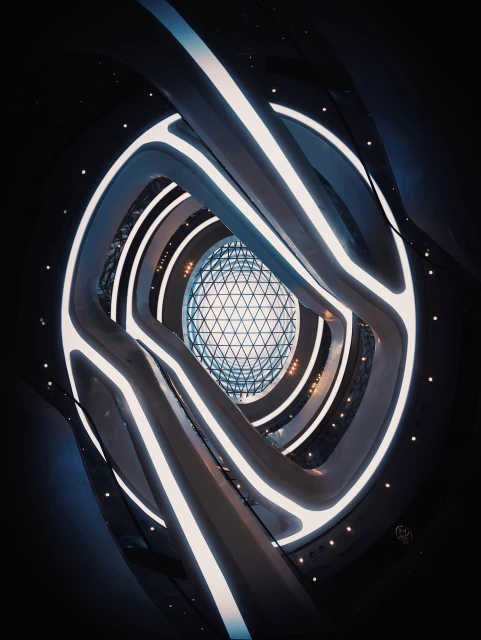 Interior view of a modern building with curved architecture, featuring illuminated white panels and a central geodesic dome.