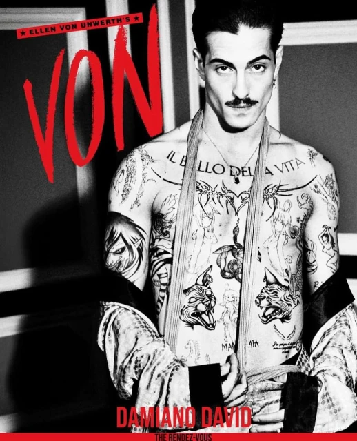 Shirtless man with tattoos stands indoors.  Black and white photo with red text overlay. Striped jacket is draped over shoulders.