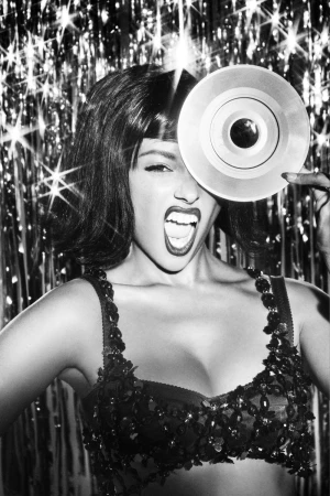Monochrome portrait of a woman holding a vinyl record over her eye against a shimmering tinsel backdrop