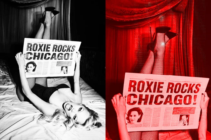 Person lying on bed, holding newspaper with headline ROXIE ROCKS CHICAGO! High-heeled shoes and fishnet stockings visible.