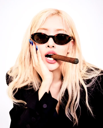 Blonde woman wearing oval sunglasses biting a cigar with blue nails against a white background