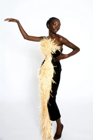 Black woman wearing a strapless black dress adorned with a textured straw appliqué by Ellen Von Unwerth
