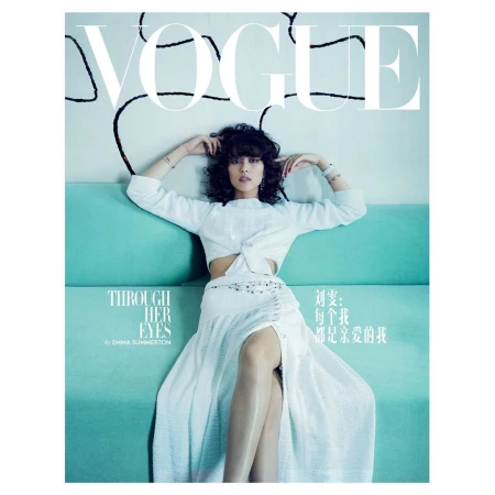 Woman in white two-piece outfit posing on a turquoise sofa with Vogue magazine typography overlay