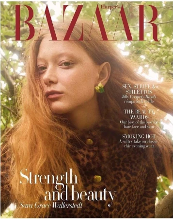 Close-up portrait of red-haired model Sara Grace Wallerstedt outdoors among green foliage for Harper's Bazaar magazine cover.