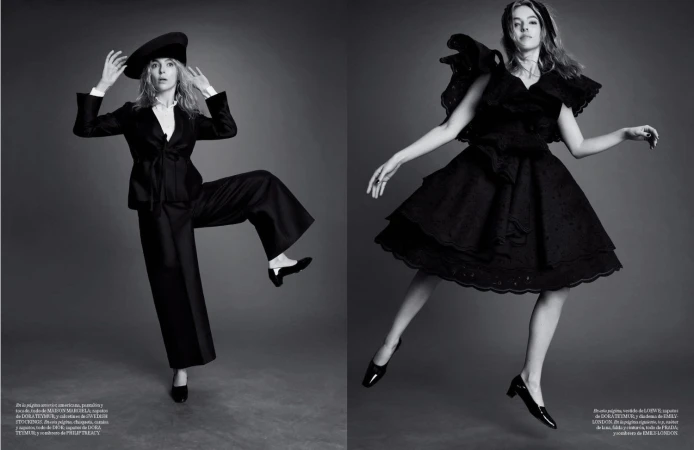 Two women in black dresses and hats pose against a grey backdrop in a monochrome fashion photograph for a magazine spread.