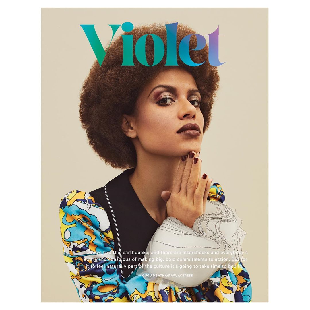 Magazine cover featuring a portrait of Gugu Mbatha-Raw, an actress, with her hands raised, wearing a colorful dress and dark lipstick.