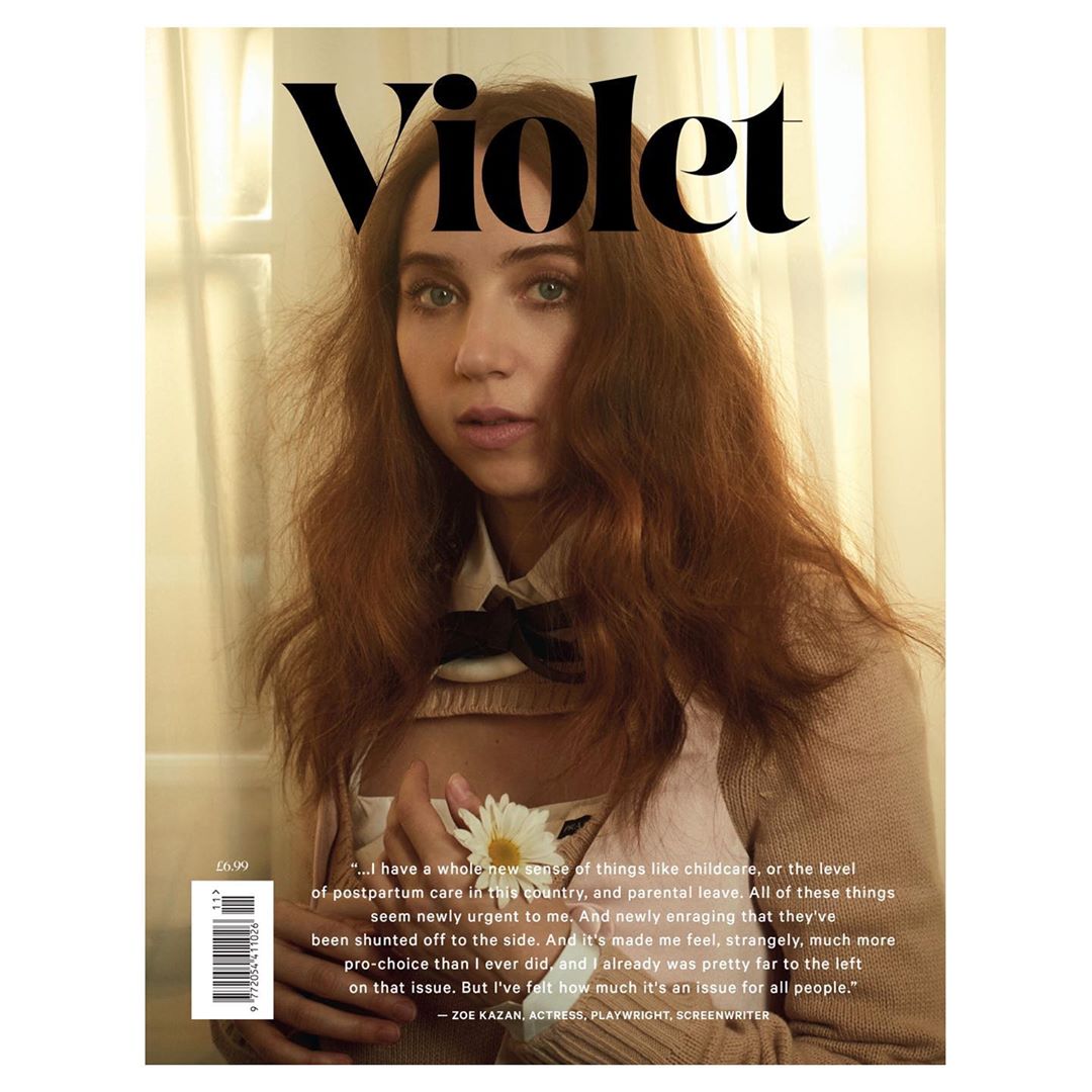 Magazine cover featuring a portrait of a young adult woman with long red hair, holding a white flower, and wearing a neutral-toned top.