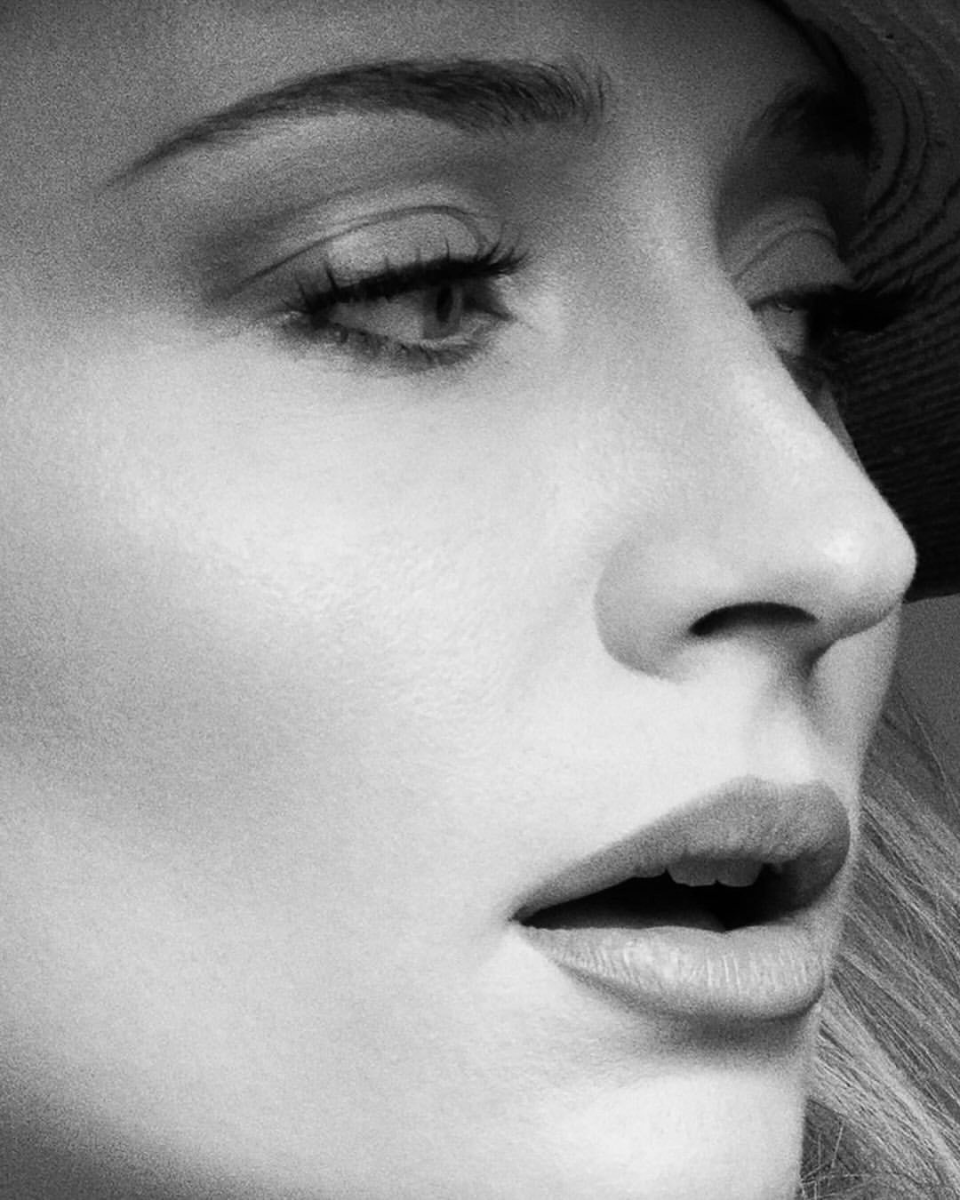 Black and white close-up portrait of a fair-skinned woman with parted lips, visible lashes, and subtle facial contouring.