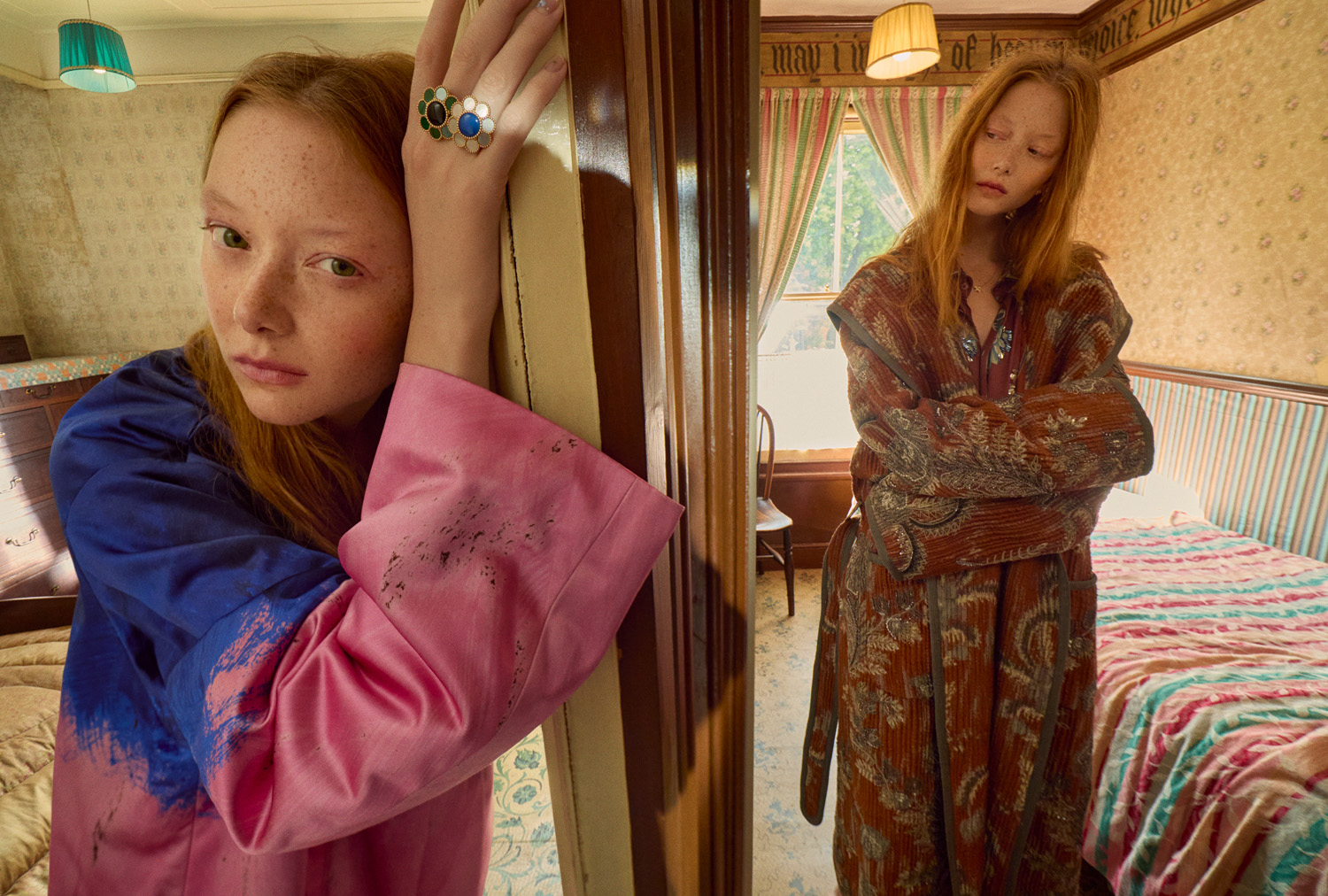 Two red-haired women pose indoors. One woman is visible through a doorway in a pink-and-blue shirt, the other in a printed coat.