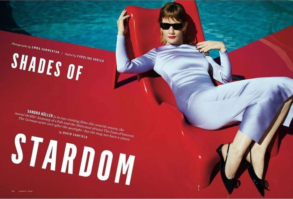 Sandra Hüller lounges in Vanity Fair editorial poolside, wearing a chic lilac dress and sunglasses, exuding effortless glamour.