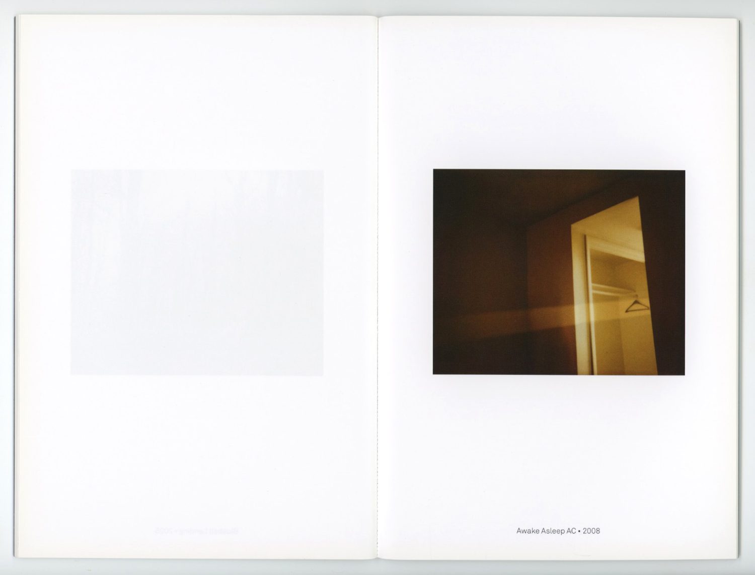 An open book shows an interior photograph of a dark, vacant room with an open closet and a blank white space on the opposite page.