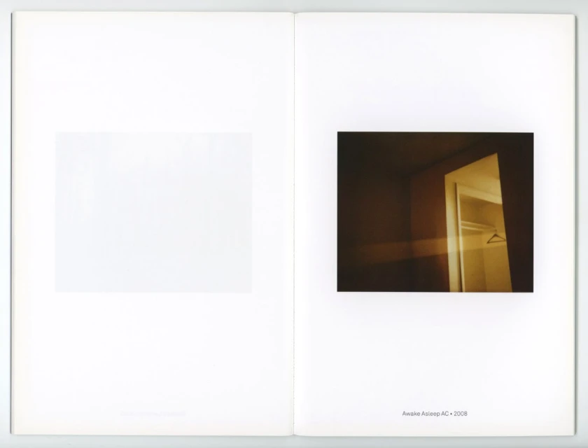 An open book shows an interior photograph of a dark, vacant room with an open closet and a blank white space on the opposite page.