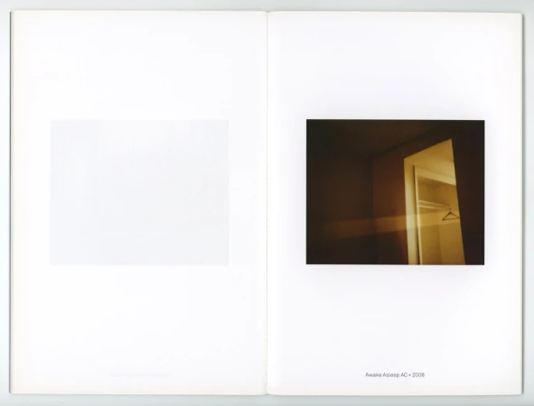 An open book shows an interior photograph of a dark, vacant room with an open closet and a blank white space on the opposite page.