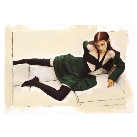 Fashion editorial shot of a reclining adult female wearing a black top, green skirt, jacket, and high black boots on a white couch.