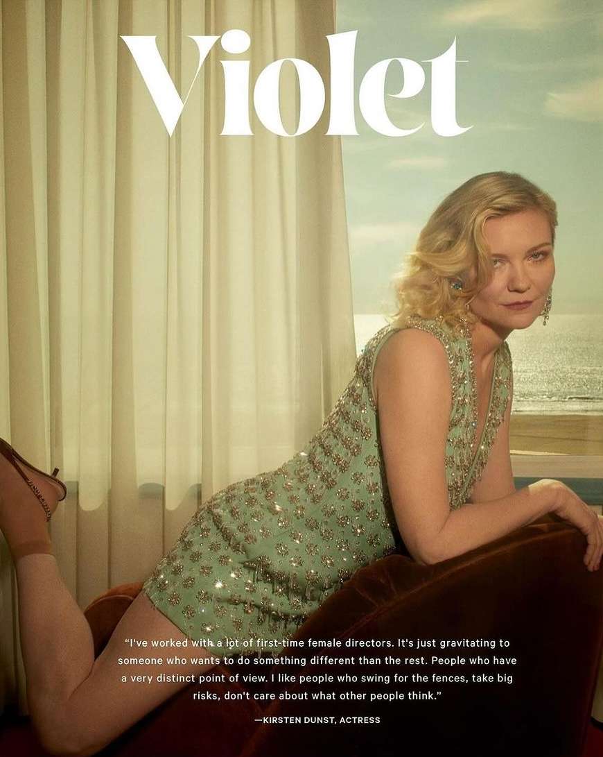 Kirsten Dunst poses in a beaded dress in front of a window with an ocean view in a celebrity and entertainment editorial shot.