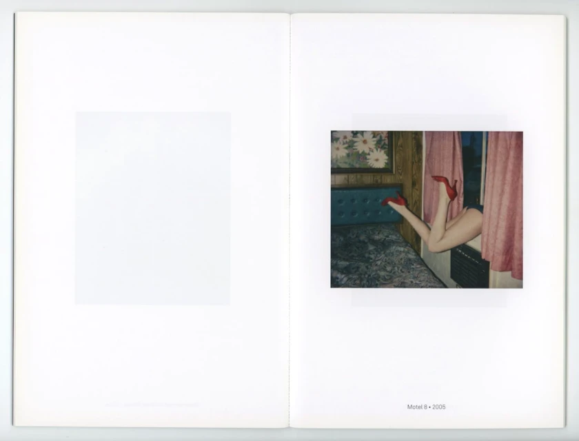 Open book page with photo of woman's legs in red high heels emerging from behind pink curtains into a hotel room with floral wallpaper.
