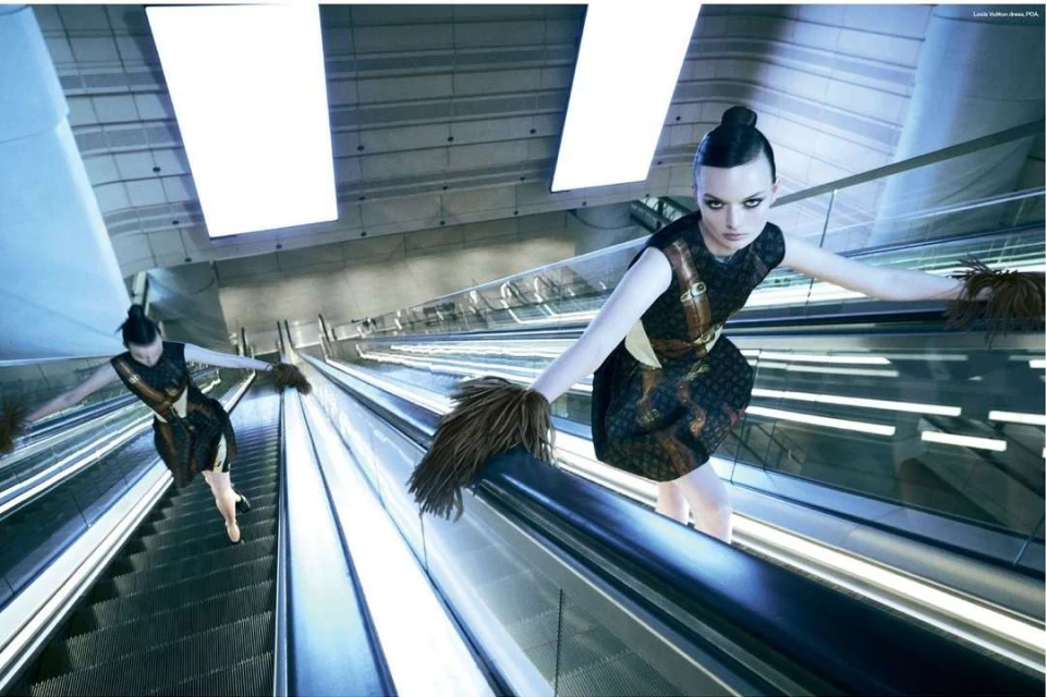 Fashion shot of a woman in a dress on an escalator with outstretched arms, duplicated with a fisheye lens and futuristic interior.
