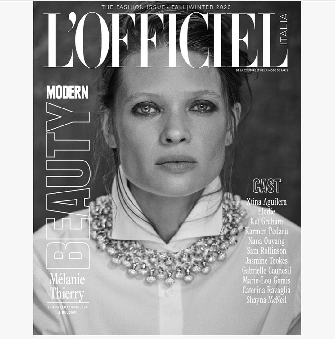 Black and white portrait of a woman wearing a white collared shirt and a heavy jewelled necklace