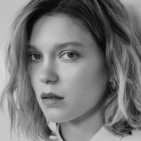 Close-up monochrome portrait of a woman with shoulder-length wavy hair and small hoop earrings looking at camera.