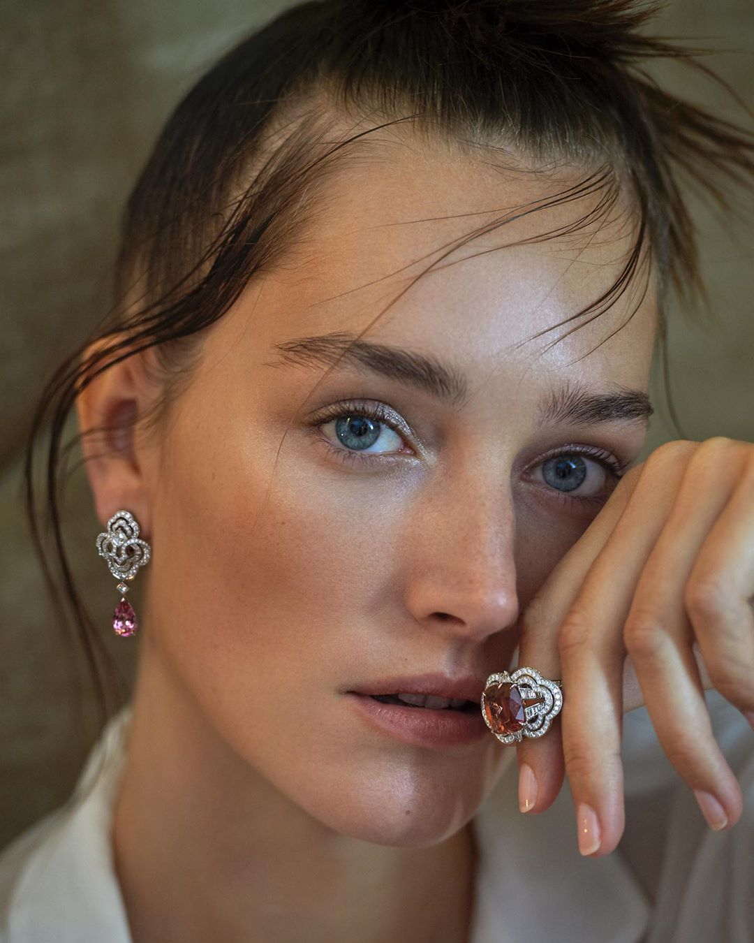 Close-up of a fair-skinned woman with blue eyes wearing earrings and a ring, fashion photography for beauty or jewellery advertising.