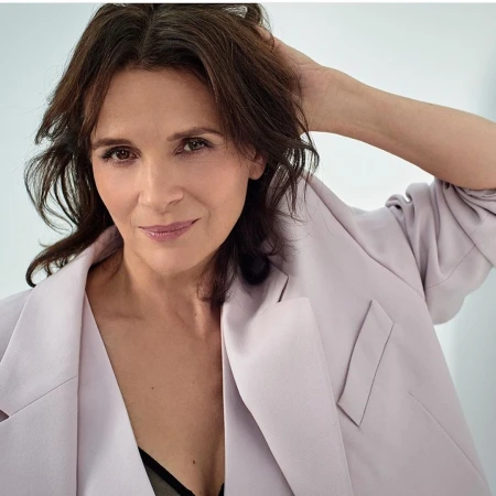 Elegant woman in a lilac blazer strikes a pose, hand gracefully placed behind her head, complemented by her dark hair and soft makeup.
