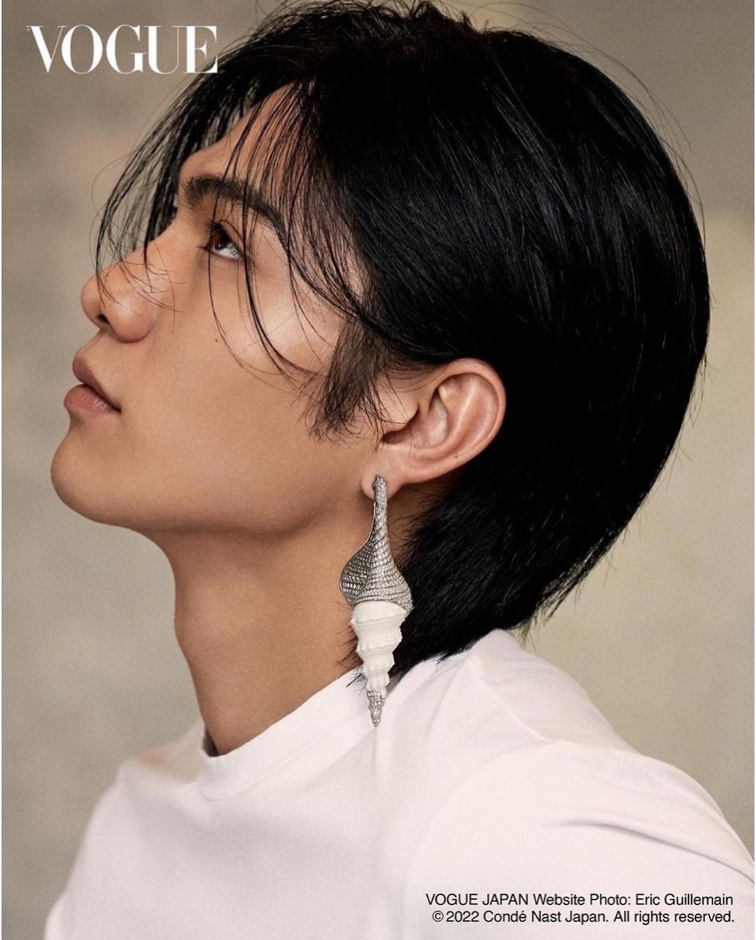 Profile portrait of a young man with dark hair wearing a large shell earring by photographer Eric Guillemain
