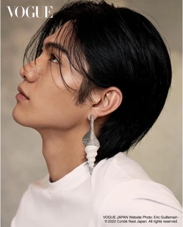Profile portrait of a young man with dark hair wearing a large shell earring by photographer Eric Guillemain