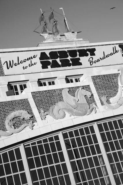 Architectural monochrome shot of the Asbury Park Boardwalk building featuring a decorative ship model and winged seahorse statues.