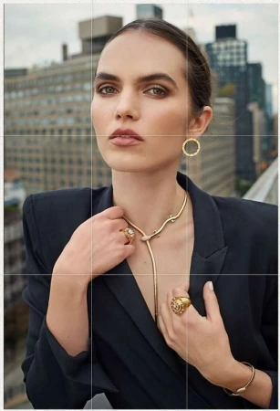 Portrait of a woman wearing a dark blazer and gold jewelry against a city skyline background by Eric Guillemain