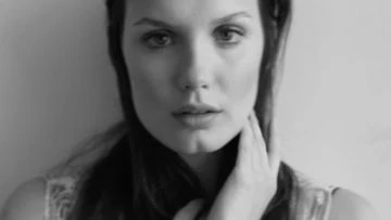 Close-up black and white portrait of a woman with her hand touching her neck by Eric Guillemain