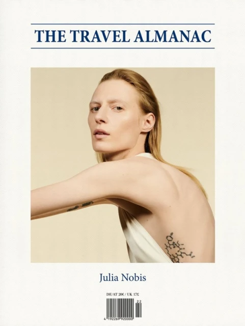 Magazine cover featuring woman with a tattoo on her back, light skin, long blond hair against an off-white background. 