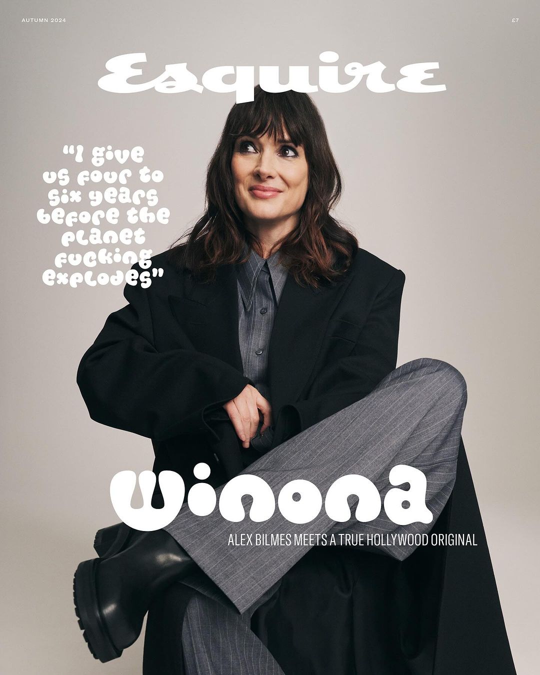 Magazine cover featuring Winona Ryder wearing a black jacket and grey striped pants, seated against a neutral background.