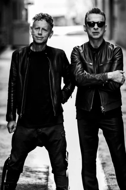 Black and white portrait of two adult males wearing leather jackets, standing in an alleyway with sunglasses, posing for fashion.