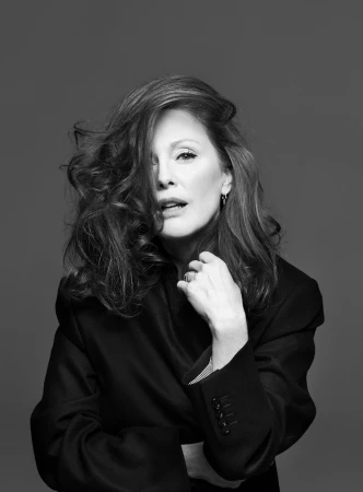Portrait of a woman with voluminous dark hair and black blazer against a grey backdrop featuring make-up by Francelle Daly