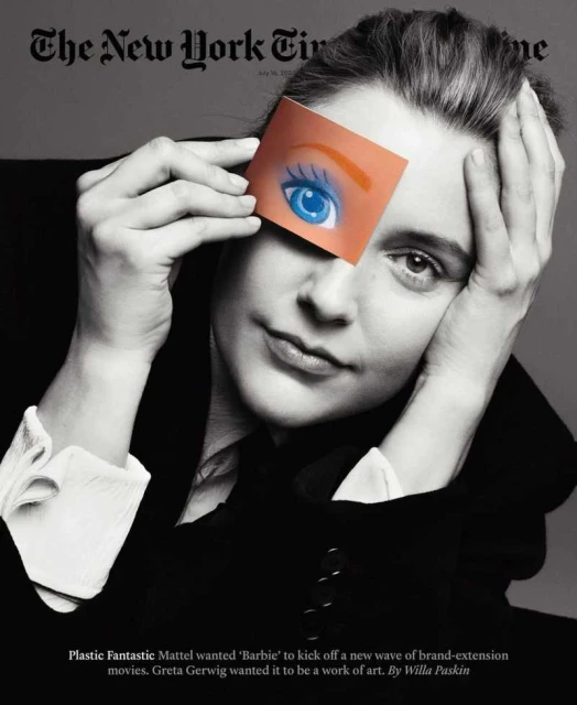Monochrome close-up of Greta Gerwig holding a Barbie eye card in front of her face, evoking a creative and artistic mood.