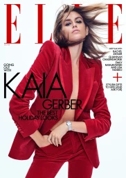 Kaia Gerber wearing a red velvet suit against a white seamless background with magazine cover typography overlay