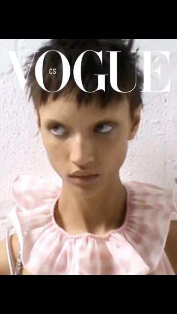 Close-up portrait of a young woman on a 'Vogue' cover, showcasing makeup and fashion against a textured white background.