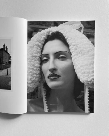 Black and white editorial portrait of a woman wearing a textured white bonnet and dark dramatic makeup